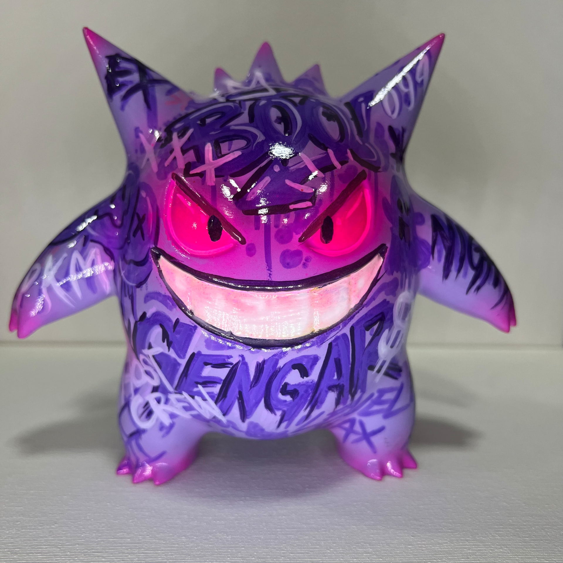 Toy art roxo com intervenções gráficas, olhos rosa e sorriso amplo, fotografado de frente