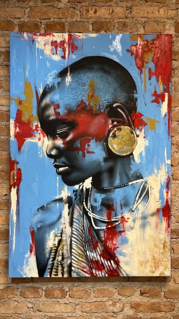 Pintura autoral de retrato feminino sobre fundo azul, apresentada junto a uma parede de tijolos