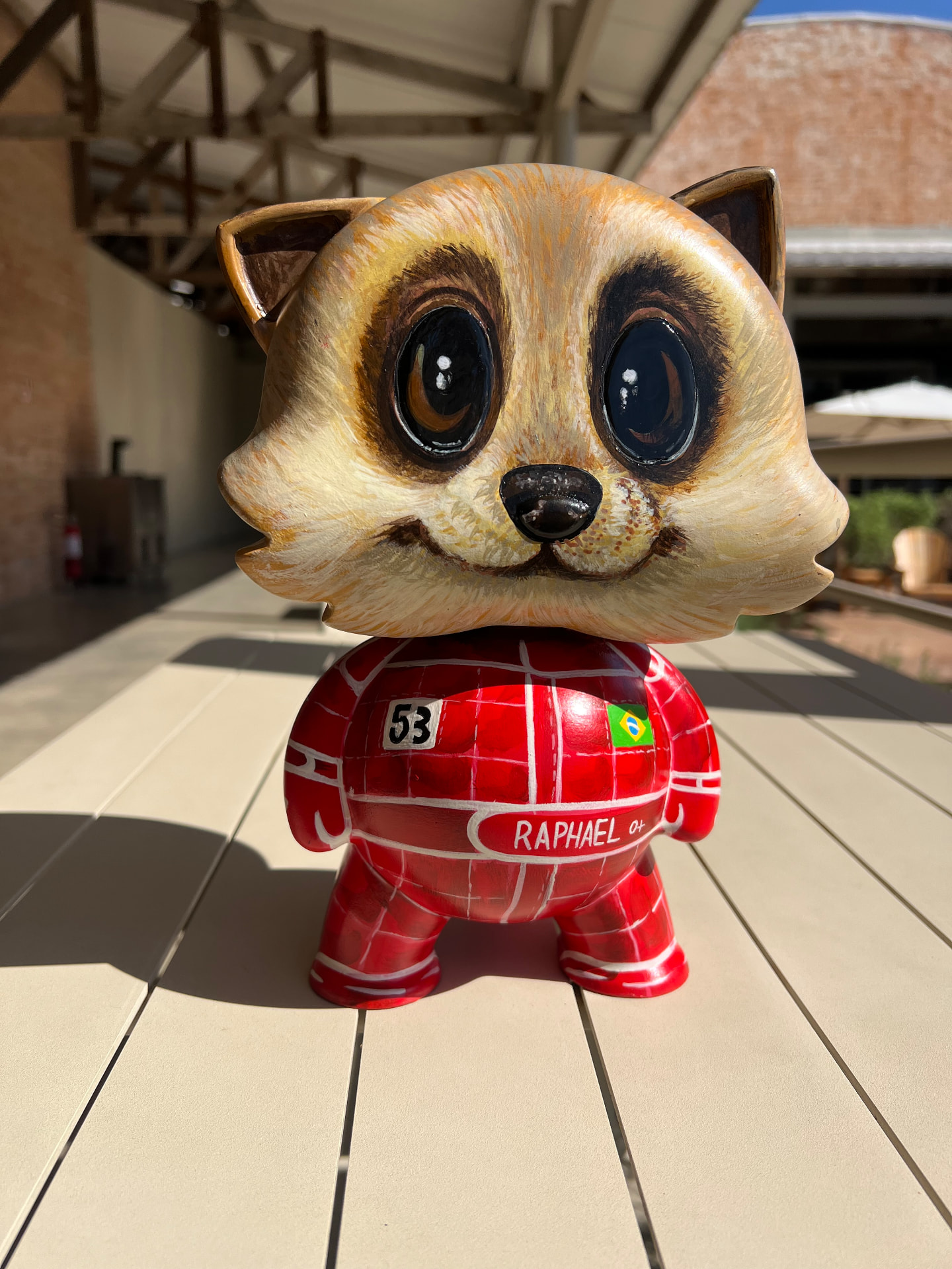 Toy art com cabeça de animal e traje vermelho de automobilismo, visto de frente