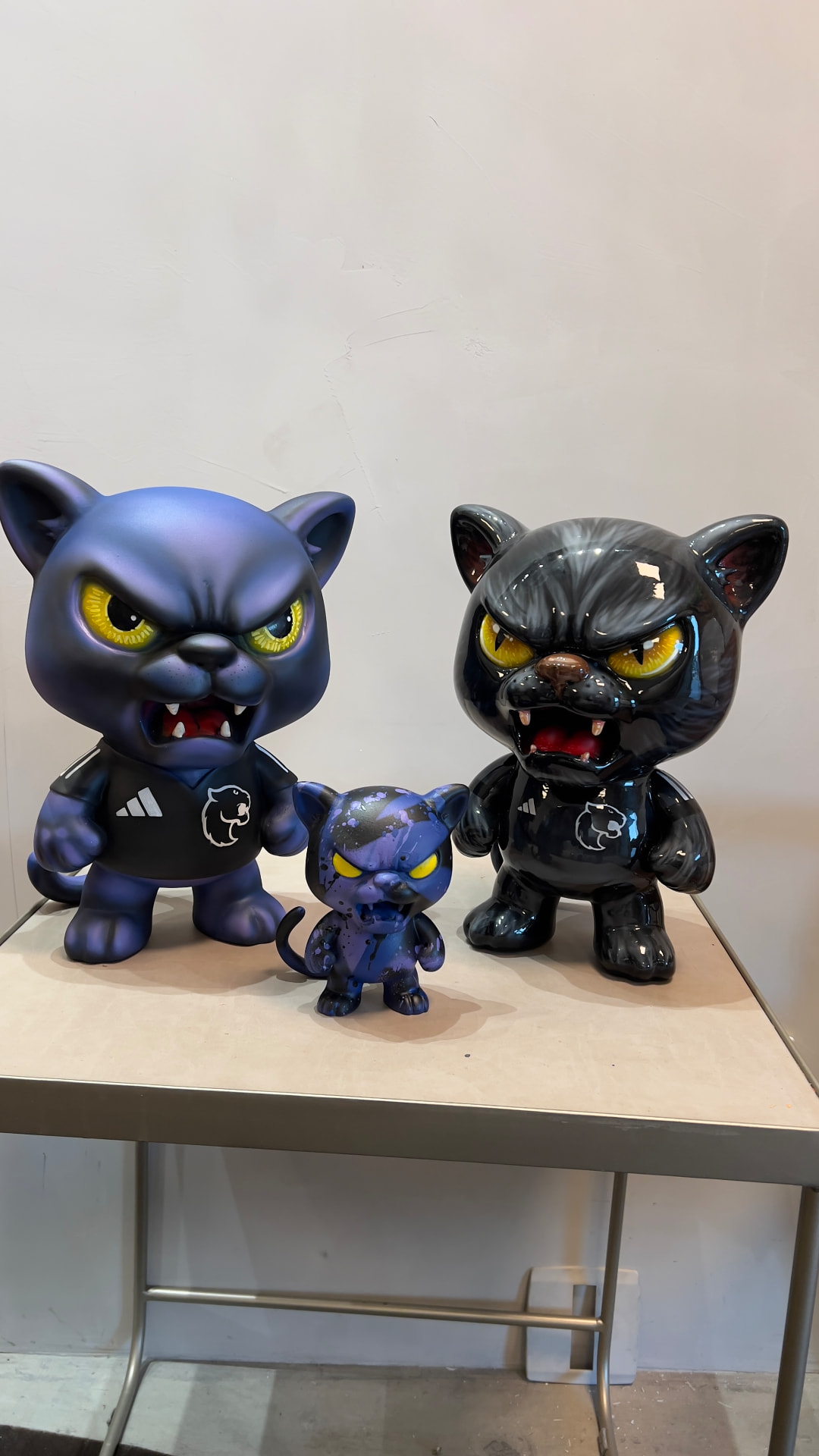 Três toy arts felinos em tamanhos diferentes, fotografados de frente